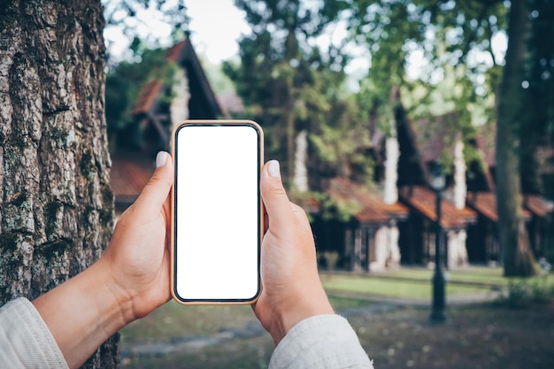 Hand met een telefoon op de achtergrond van een landhuis