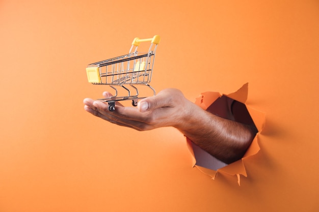 Hand met een trolley op oranje achtergrond