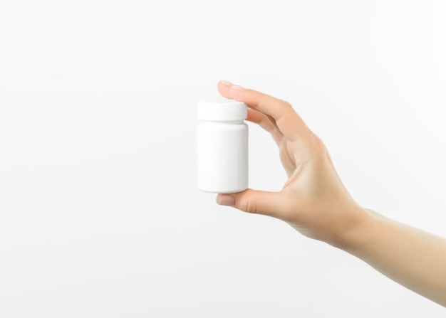 Foto hand met een witte plastic pot met pillen op een witte achtergrond