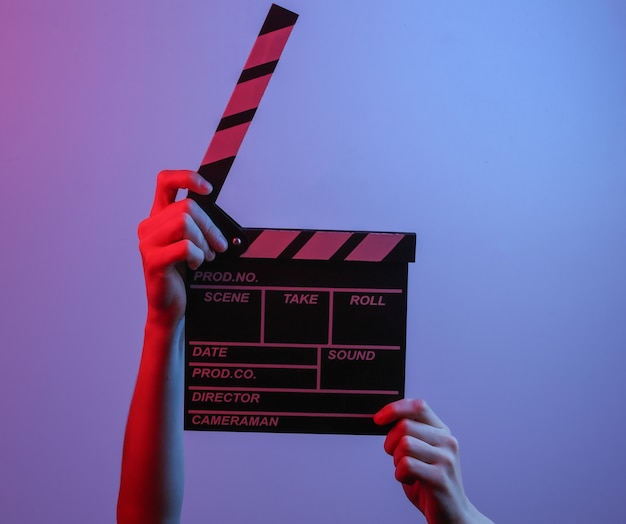 Hand met film klepel bord in blauw rood neonlicht. bioscoopindustrie, entertainment.