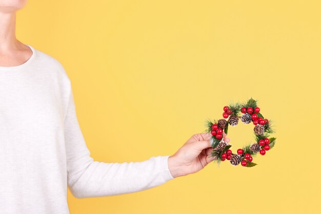 Hand met geïsoleerde de decoratie van de kerstmiskroon