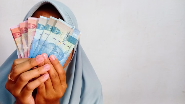 Hand met geld in Indonesische roepia na ontvangst van THR Tunjangan Hari Raya, Eid Mubarak Bonussen voor moslimmedewerker THR