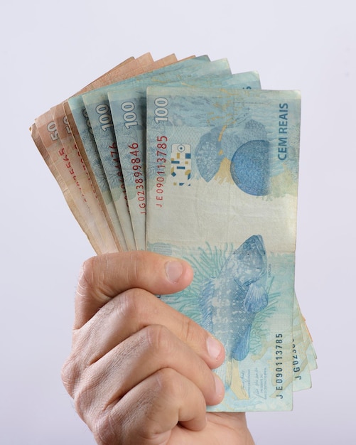 Hand met geld zeshonderd reais Braziliaanse valuta op witte achtergrond