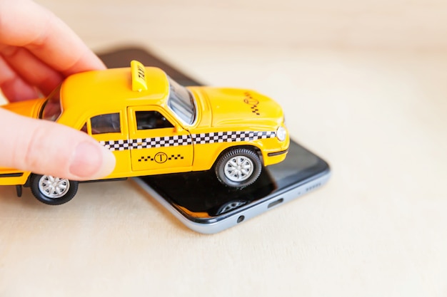 Hand met gele speelgoedauto op een smartphone
