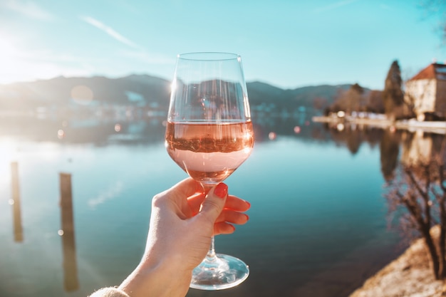 Hand met glas wijn op de meerachtergrond in Alpiene bergen in Beieren, Duitsland