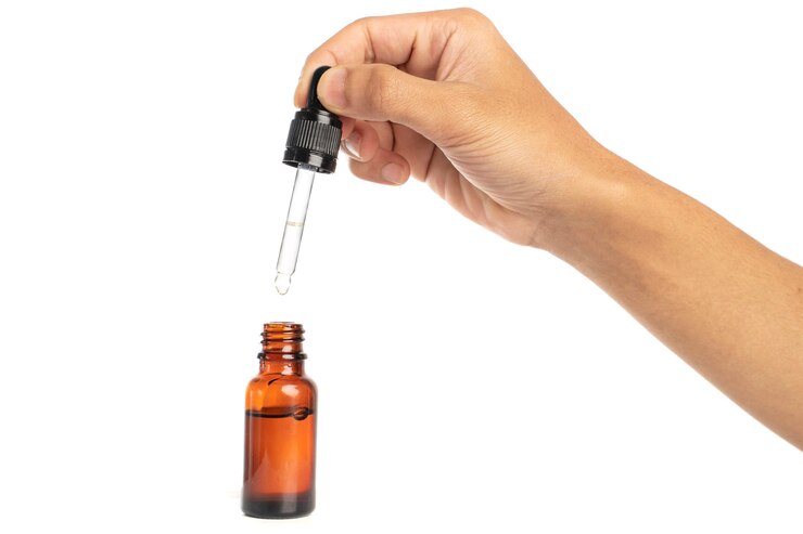 hand met glazen pipet etherische oliën fles geïsoleerd op een witte achtergrond