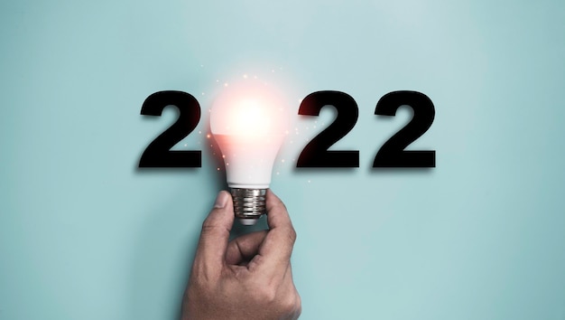 Hand met gloeilamp met 2022 jaar voor gelukkig nieuwjaar idee en creatief denkconcept.