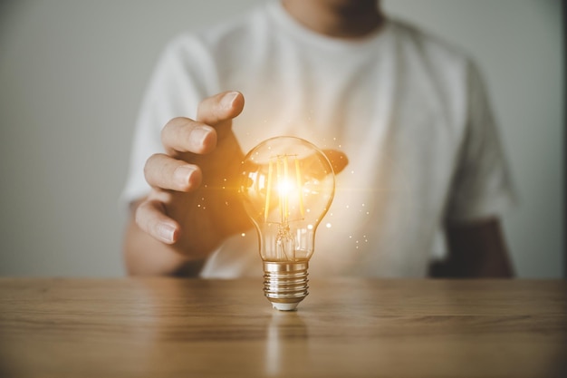 Foto hand met gloeilamp op houten tafel concept van inspiratie creatief idee denken en toekomstige technologische innovatie