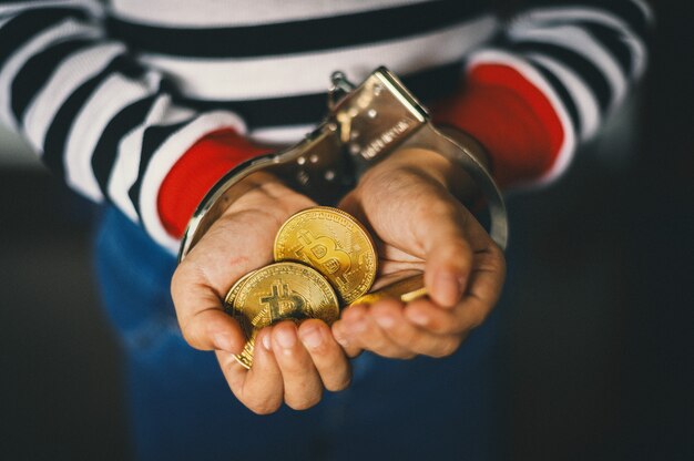 Hand met gouden bitcoin. criminele man met handboeien na een misdrijf gepleegd