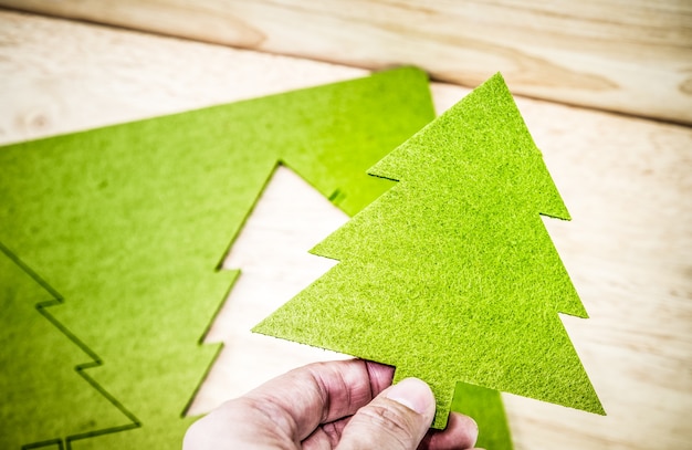 Foto hand met groene kerstboom met houten tafel op de achtergrond