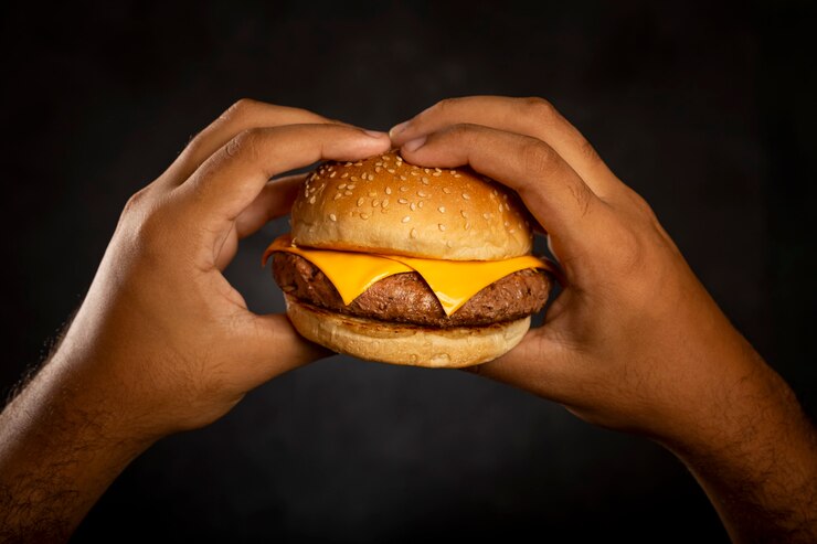 Hand met hamburger op donkere achtergrond