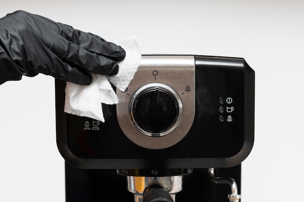 Hand met handschoenen die espressomachine desinfecteren