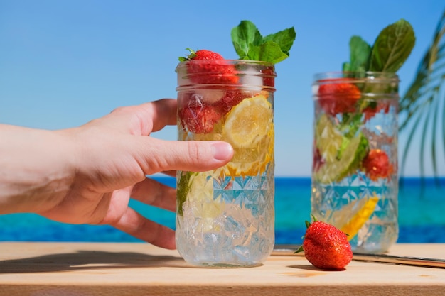 Hand met harde seltzercocktails op tropisch strand