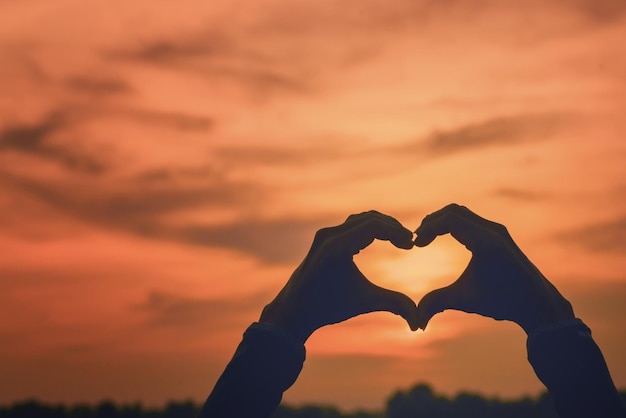 Foto hand met hartvorm tegen de hemel bij zonsondergang