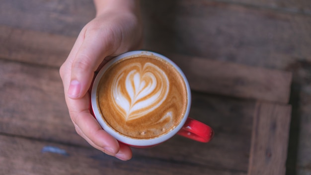 Hand met hete latte koffie