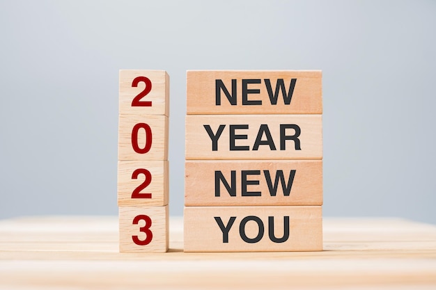 Hand met houten blok met tekst 2023 NEW YEAR NEW YOU op tafelachtergrond Resolutie strategie doel bedrijfs- en vakantieconcepten
