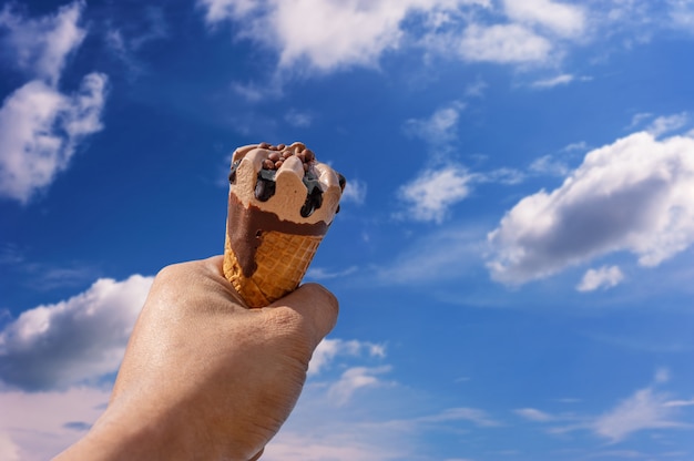 Hand met ijs op de vage blauwe achtergrond van de hemelaard