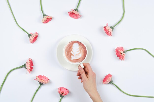 Hand met koffiekopje met bloemen