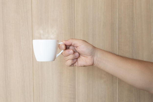 Foto hand met koffiekopje op houten achtergrond