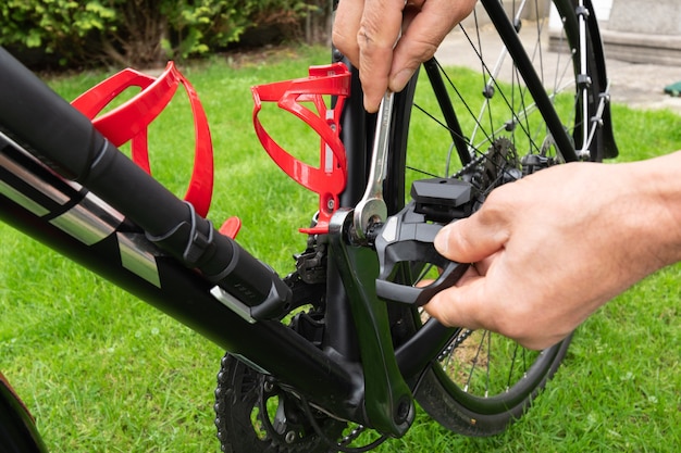 Hand met moersleutel fietspedalen op het gras bevestigen