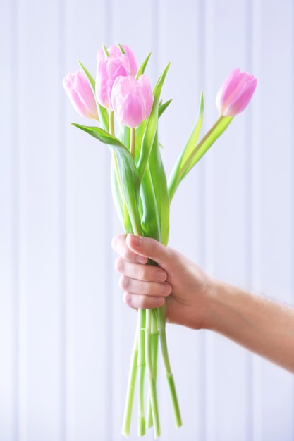 Hand met mooie roze tulpen op houten achtergrond