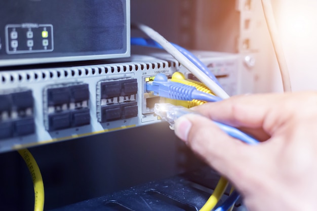 Hand met netwerkkabels aangesloten op servers in een datacenter