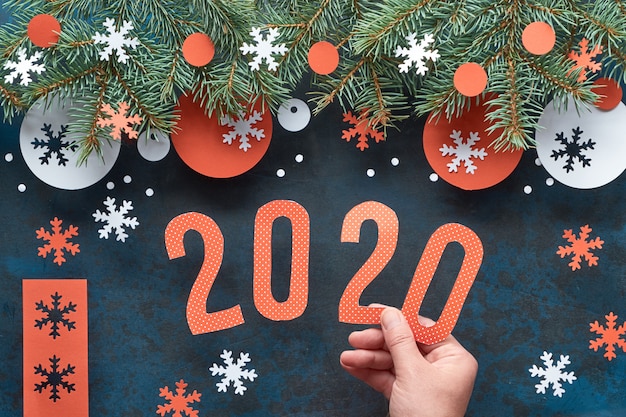 Hand met nummer 2020, Kerstmisachtergrond met spartakjes, rode en Witboekdecoratie