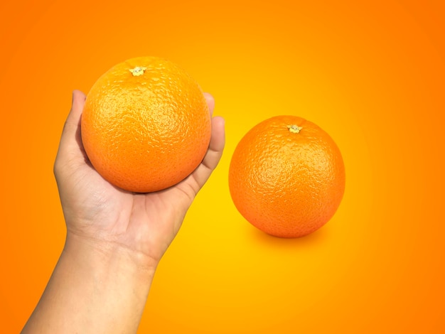 Hand met oranje fruit en stukjes sinaasappel op oranje achtergrond