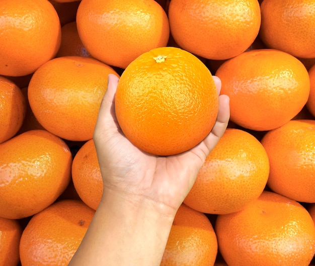 Hand met oranje fruit op achtergrond oranje fruit