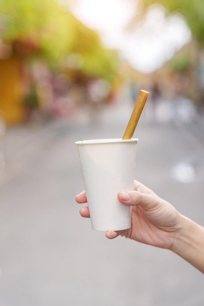 Hand met papieren kopje kruidendrank met lotusblaadje en theeblad is de meest populaire drank voor toeristen in de oude stad Hoi An in centraal Vietnam