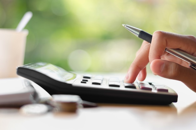 hand met pen en dringende calculator knop voor zakelijke boekhouding van Financiën