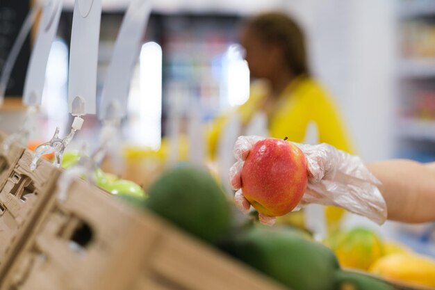 Hand met plastic handschoenen die het fruit op de markt kiezen