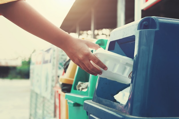 Hand met plastic handvatten dumpen in de prullenbak