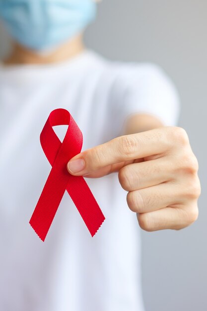 Hand met Red Ribbon voor december Wereldaidsdag (acquired immune deficiency syndrome), multipel myeloom Cancer Awareness-maand en National Red Ribbon-week. Gezondheidszorg en wereldkankerdagconcept