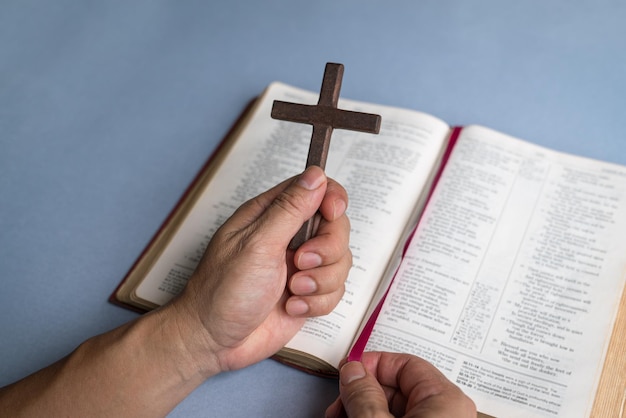 Hand met religieus kruisbeeld kruis bovenop de Heilige Bijbel