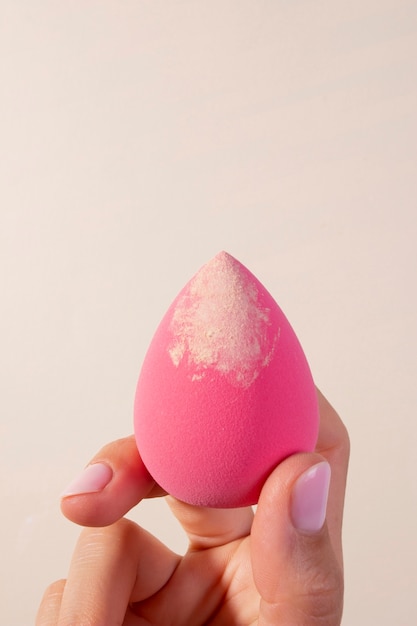 Hand met roze beautyblender met foundation