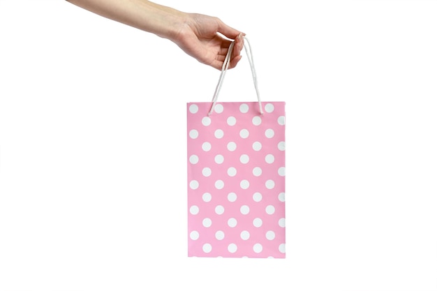 Hand met roze polka dot tas op witte achtergrond. presentatie van het geschenk. aankoop in verpakking