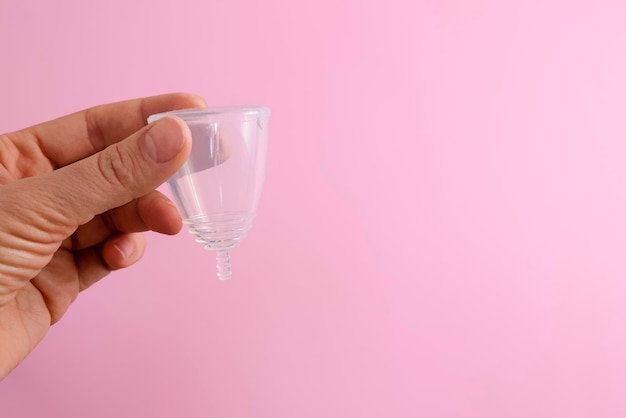 Hand met siliconen menstruatiecup op roze achtergrond