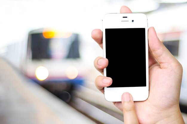 Foto hand met slimme telefoon over onscherpte metro station achtergrond