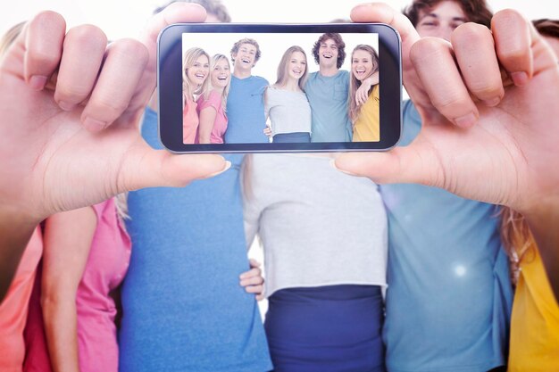 Hand met smartphone die tegen een groep vrienden toont die elkaar vasthouden en glimlachen