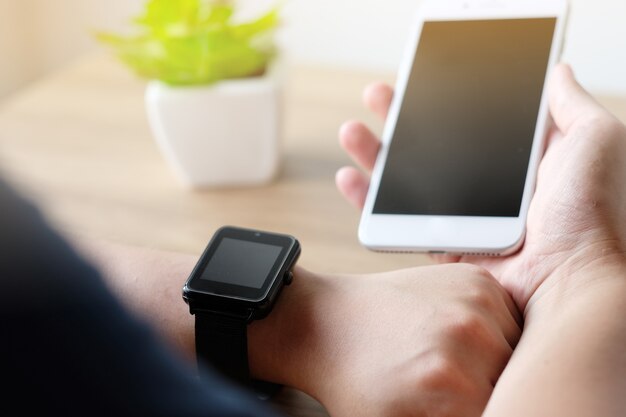 Hand met smartphone en smartwatch