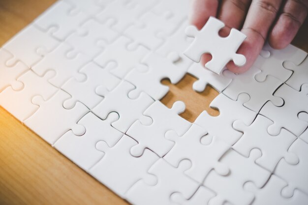 Hand met stuk van de lege puzzel met papier frame achtergrond.