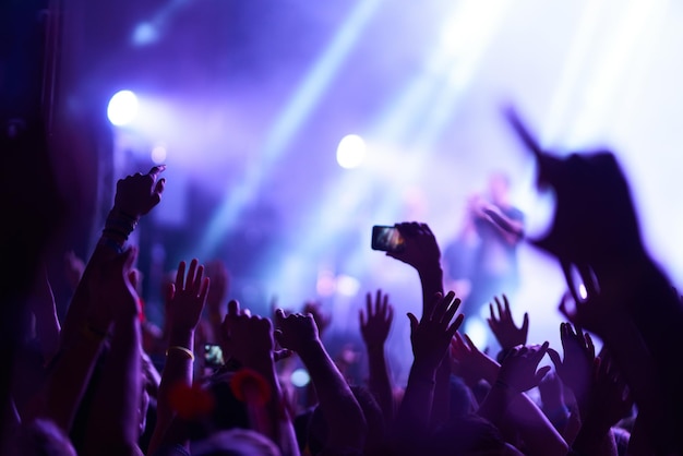 Hand met telefoon neemt livemuziekfestival op Mensen nemen foto met smartphone tijdens concert