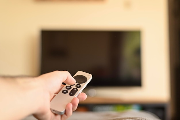 Hand met tv-afstandsbediening televisie inschakelen thuis smart tv selectieve focus