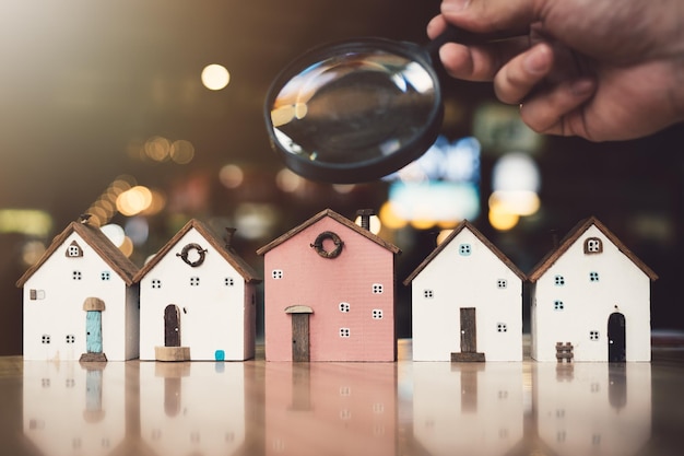 Hand met vergrootglas en kijken naar huis model huis selectie onroerend goed concept