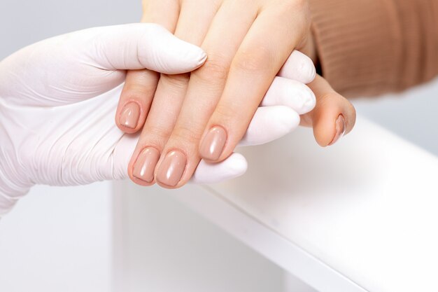 Hand met vrouwelijke vingers met beige manicure