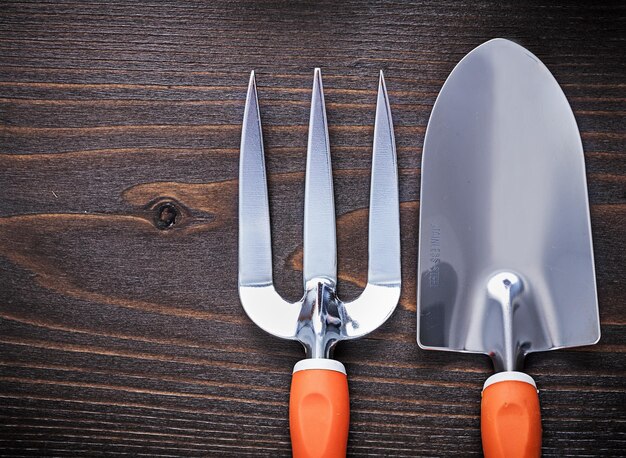 Hand metal spade and trowel fork with handles on vintage wooden surface gardening concept