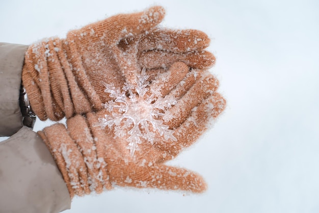 装飾的な透明な雪の結晶を持ってミトンを手に