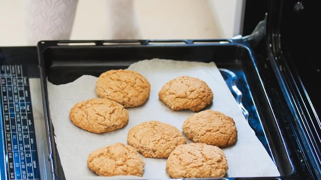 Hand in the mitten pulls out of the oven homemade cookies close up