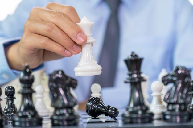 Foto la mano muove gli scacchi con la strategia e la tattica per vincere la battaglia di gioco del nemico sul concetto di sfida strategica della concorrenza di opportunità di business del gioco da tavolo